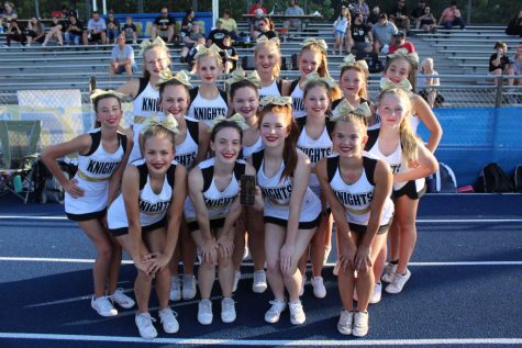 The cheer squad posing in front of the bleachers at an away football game