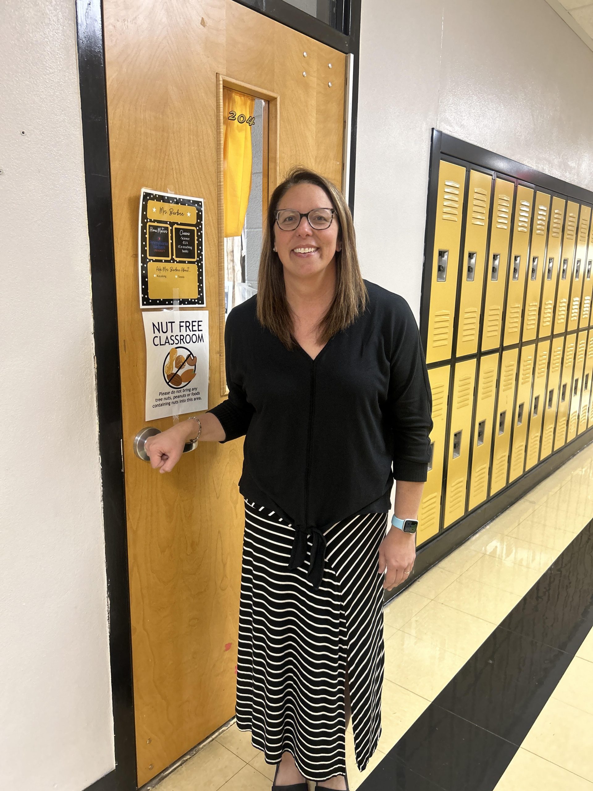 Mrs. Kelly stands proudly outside of her classroom.