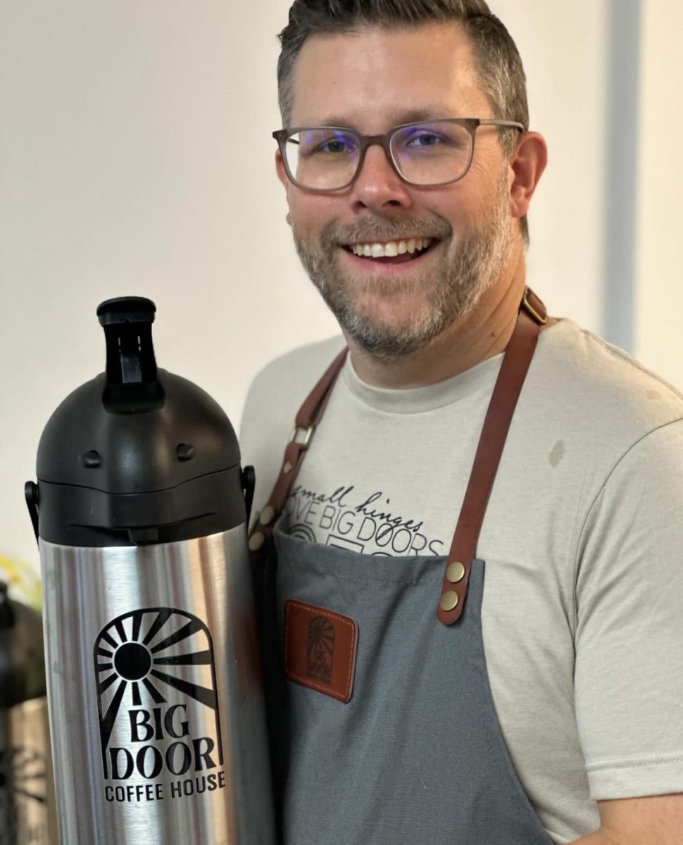 Jason grinning for a photo while making coffee for Big Door Coffeehouse. 