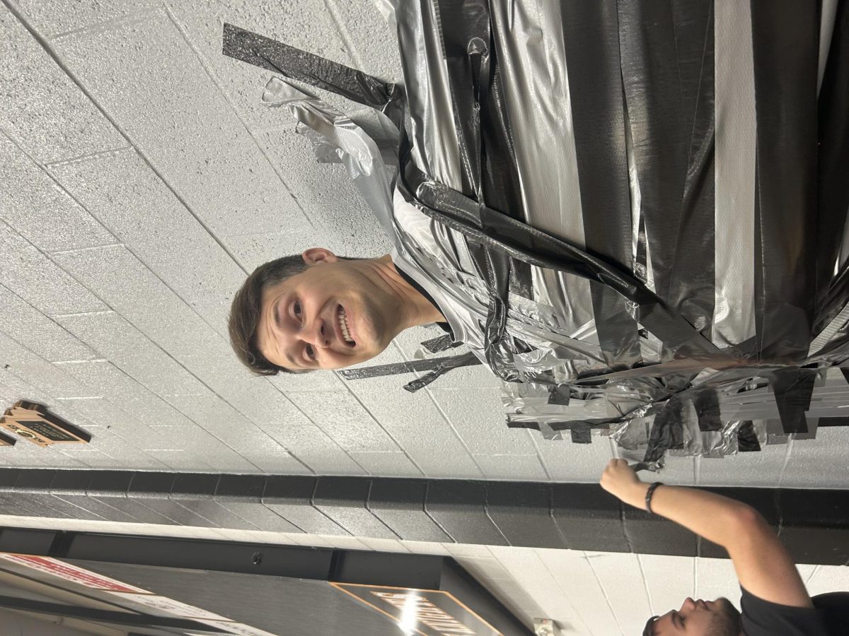 Mr. Upchurch being taped on the wall at the 2025 EOC Carnival