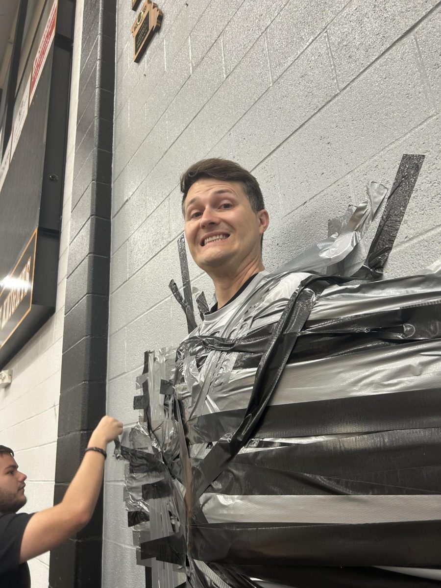Mr. Upchurch being taped on the wall at the 2025 EOC Carnival